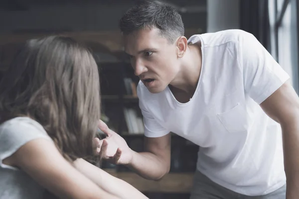 Um homem com uma t-shirt branca olha com raiva para a menina de cabelos escuros — Fotografia de Stock