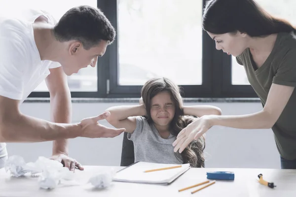 Um homem e uma mulher repreendem uma menina que se senta ao lado dele na mesa, cobrindo seus ouvidos com as mãos — Fotografia de Stock