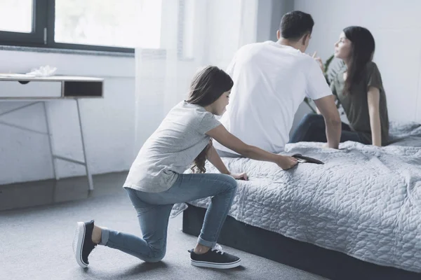 Enquanto os pais estão sentados na cama e discutindo algo, uma menina tenta roubar dinheiro da bolsa — Fotografia de Stock