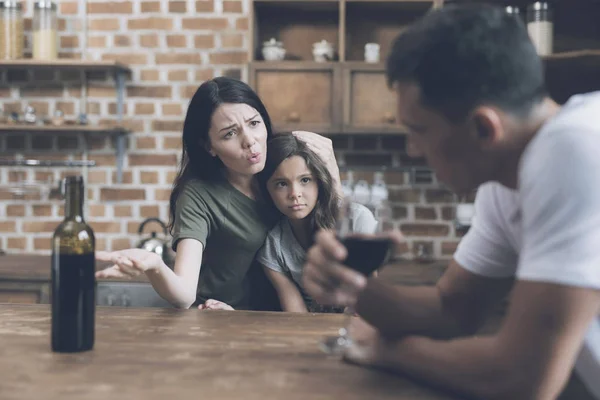 Een man is zitten en zijn vrouw, die hun dochter is knuffelen en reproachfully kijkt naar hem te kijken — Stockfoto