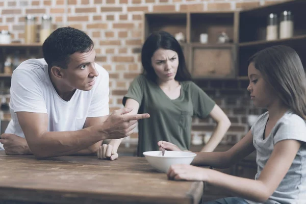 The father is talking with his sad daughter, who is sitting at the table and does not want to eat his breakfast — Stock Photo, Image