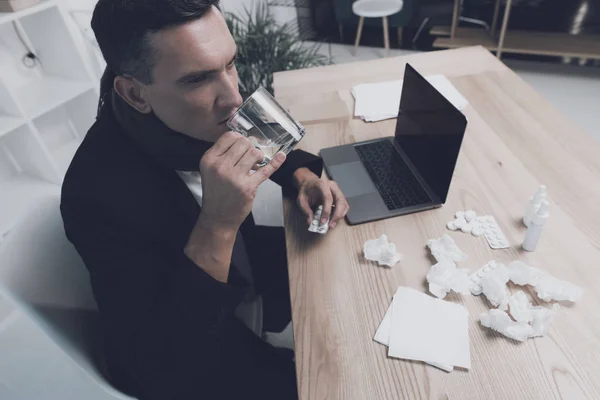 Hasta bir adam ofiste onun işyerinde oturuyor. O bir hap ve bir su bardağı elinde vardır — Stok fotoğraf