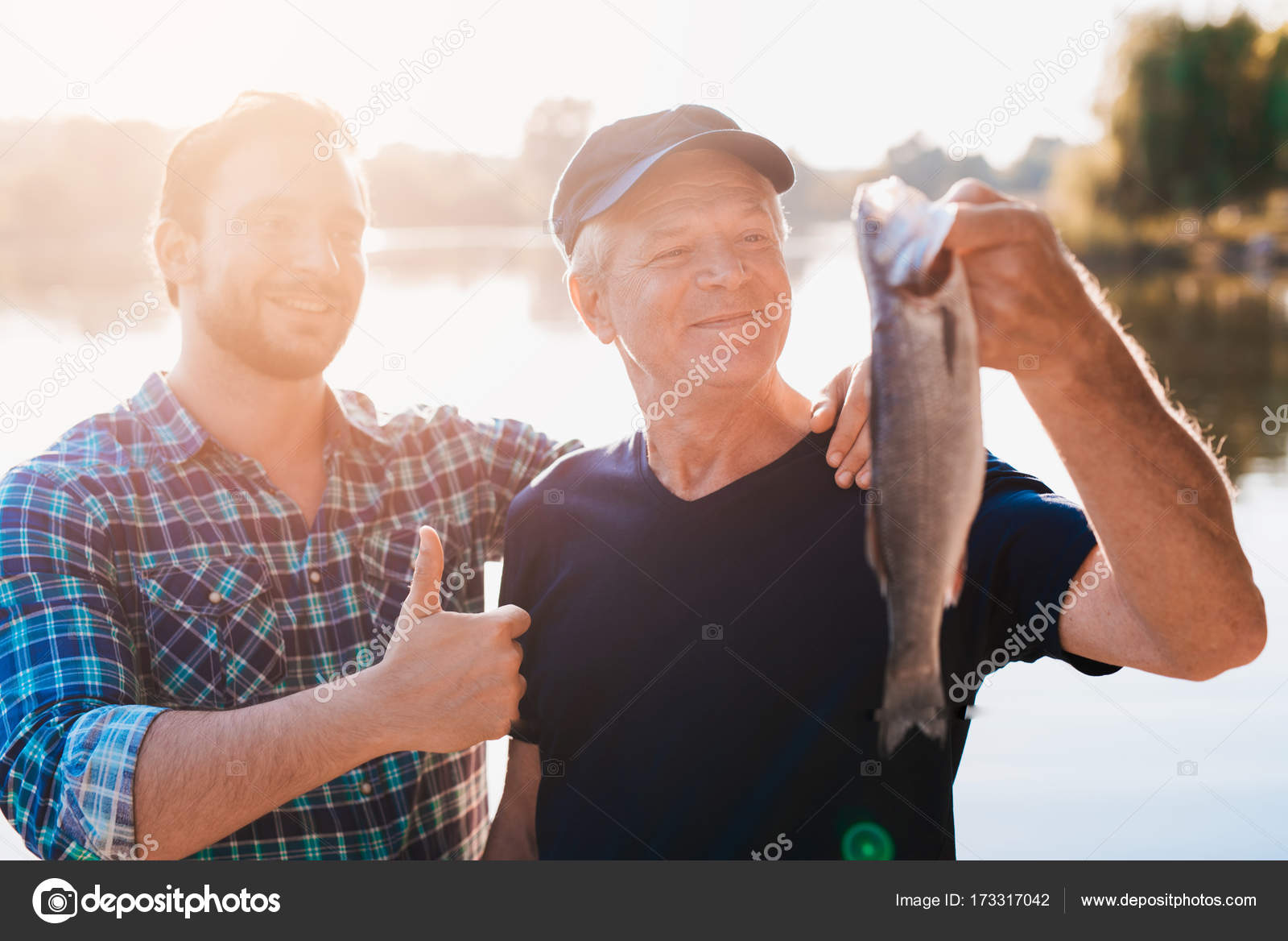 Thumbs up. The old man is holding a fish. A man stands behind him with his  thumb up — Stock Photo © vadimphoto1@gmail.com #173317042