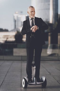 Yaşlı adam sokakta bir monocycle biniyor. O sıkı iş kıyafeti var