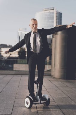 Yaşlı adam sokakta bir monocycle biniyor. O sıkı iş kıyafeti var