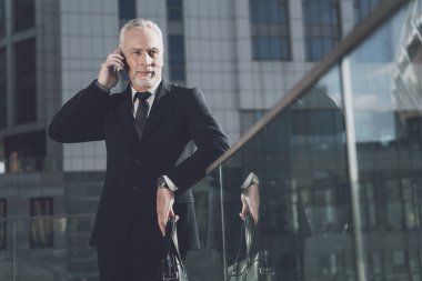 Saygın bir adam telefonda konuşurken bir takım elbise içinde sakallı