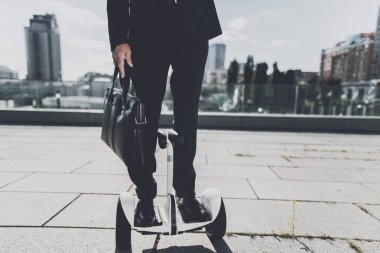 Siyah elbiseli adam şehrin içinden monowheel üzerinde hareket ediyor.