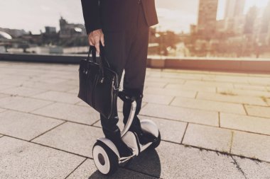 Siyah elbiseli adam şehrin içinden monowheel üzerinde hareket ediyor.