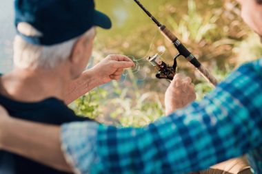 Yaşlı adam mavi gömlekli bir adam bir çizgi üzerinde yaptığı iplik çözmek yardımcı olur.