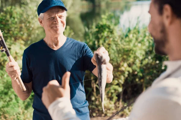 Thumbs up. The old man shows the man what a big fish he caught — Stock Photo, Image