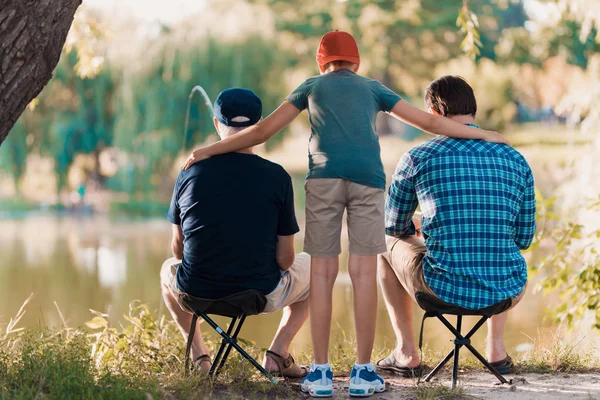 Un uomo, suo figlio e suo padre anziano stanno pescando la mattina presto sulla riva del fiume . — Foto Stock