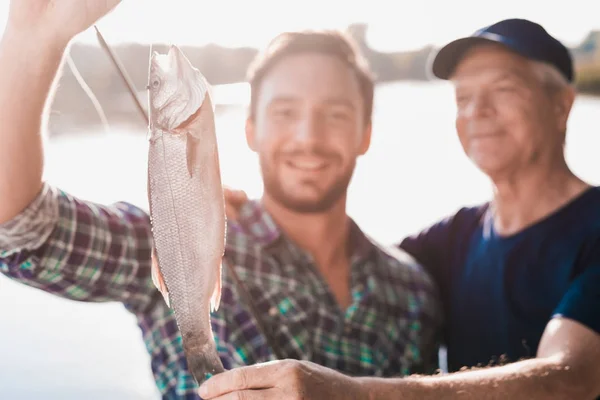 Fecha. Um homem mostra ao velho um peixe, que ele acabou de pegar em sua fiação — Fotografia de Stock