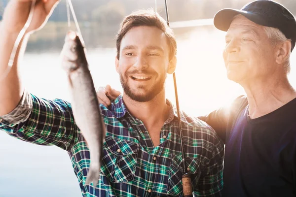 Muž a starý muž, které jsou homologní s ryby od muže proti řeky, v níž se odráží slunce — Stock fotografie