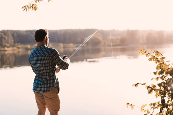 Ein Mann fischt am Ufer des Flusses. steht er mit dem Rücken zur Kamera vor dem Hintergrund des Flusses — Stockfoto