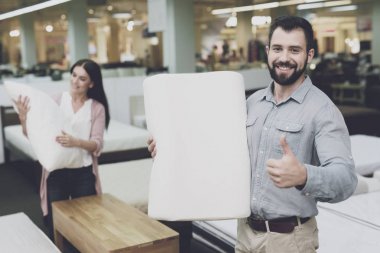 Bir çift büyük bir mağazada yataklar ve minder yastık seçer. Onlar yastık çeşitli türevleri incelemek