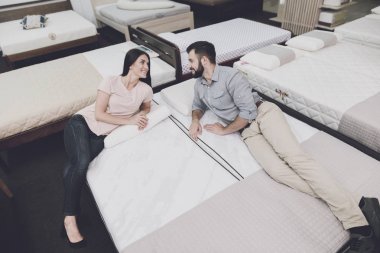 The couple came to a large mattress store to choose their own mattress. They lay down on one of them clipart