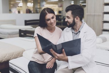 Danışman-ortopedi uzmanı bir yatak içinde belgili tanımlık stok seçin kız yardımcı olur. Mavi bir klasör elinde tutuyor