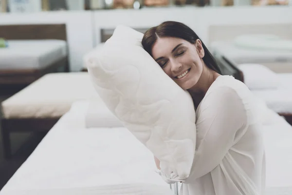 Uma mulher escolhe um travesseiro em uma grande loja. Senta-se na cama e examina-a. Ela pôs a almofada debaixo da cabeça. — Fotografia de Stock