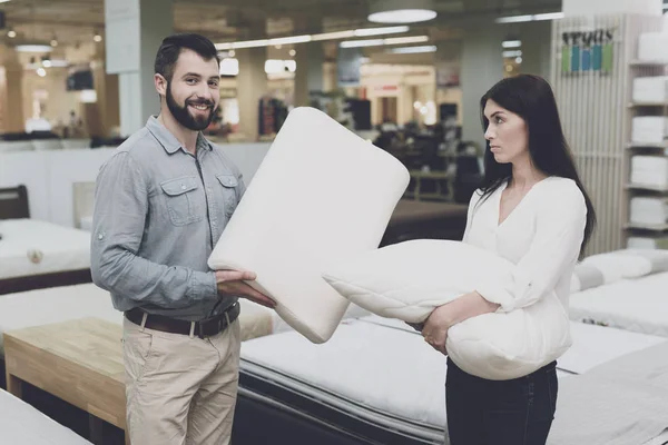 A couple in a large store of beds and mattresses chooses pillows. They examine several variants of pillows — Stock Photo, Image