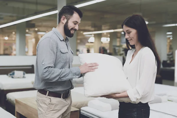 Ett par i en stor butik på sängar och madrasser väljer kuddar. De undersöka flera varianter av kuddar — Stockfoto