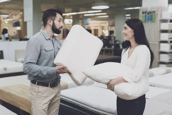 A couple in a large store of beds and mattresses chooses pillows. They examine several variants of pillows — Stock Photo, Image