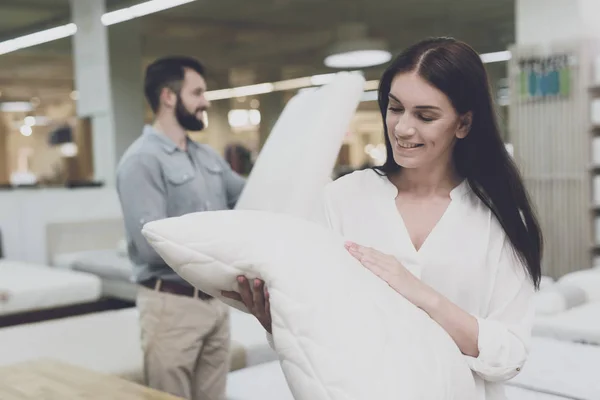 Ένα ζευγάρι σε ένα μεγάλο κατάστημα κρεβάτια και στρώματα επιλέγει μαξιλάρια. Εξετάζουν αρκετές παραλλαγές του μαξιλάρια — Φωτογραφία Αρχείου
