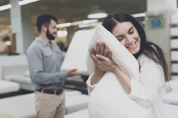 Um casal em uma grande loja de camas e colchões escolhe travesseiros. Eles examinam várias variantes de travesseiros — Fotografia de Stock