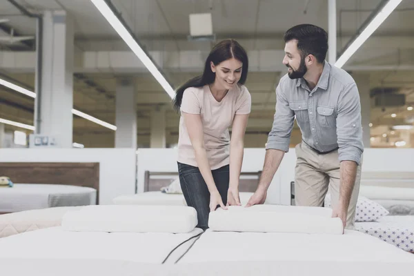 Ein Paar in einem großen Geschäft inspiziert die Matratze vor dem Kauf. sie stehen neben ihm und studieren ihn — Stockfoto