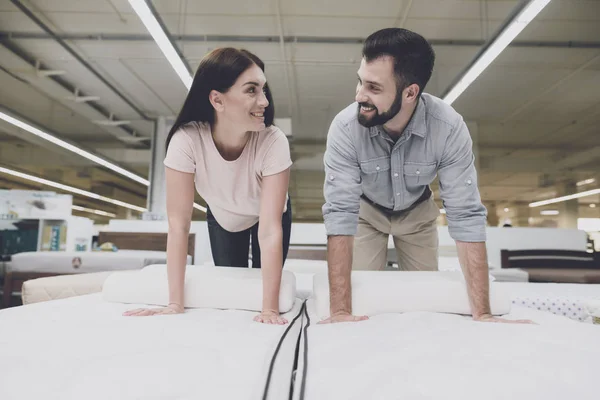 A couple in a large store inspects the mattress before buying. They are going to climb on it to try out — Stock Photo, Image