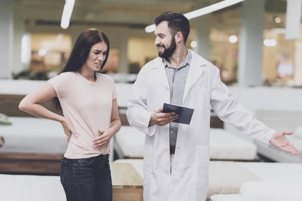 Consultor-ortopedista ayuda a la chica a elegir un colchón en la tienda. Interroga a una mujer — Foto de Stock