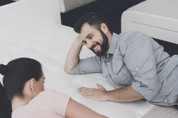 A couple chooses a mattress for themselves in the mattress store. They decided to try one and lie on it — Stock Photo, Image