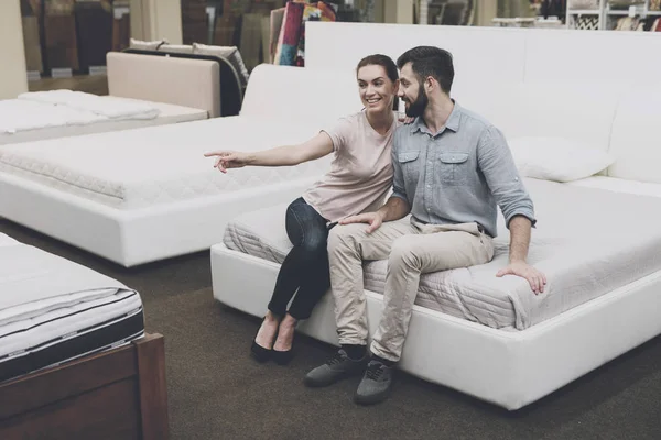 Un couple est assis sur le lit, dans une boutique de lit. Ils sont heureux. — Photo