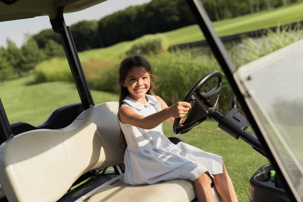 Uma menina está sentada no banco do motorista no carro de golfe — Fotografia de Stock