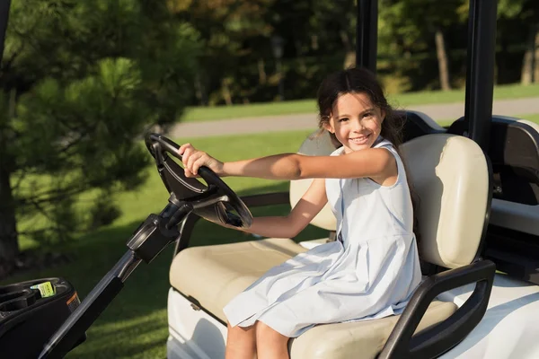 En flicka sitter på förarsätet i en vit golfbil och poser — Stockfoto