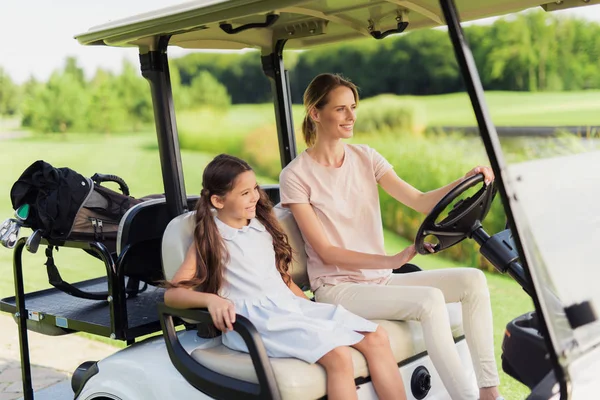 Mujer con una chica en un carrito de golf blanco que va a jugar al golf —  Fotos de Stock