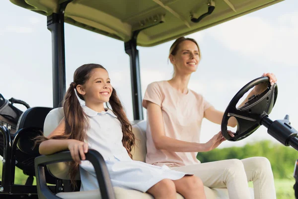 View from a low angle. A woman and a girl go to the golf cart — Stock Photo, Image