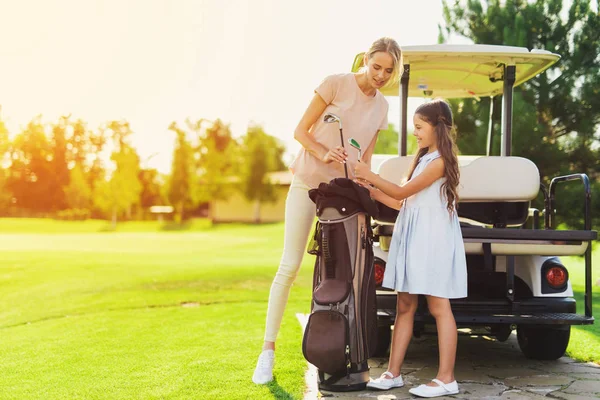 Bir kız ve bir kadın golf kulüpleri çantadan çıkar — Stok fotoğraf