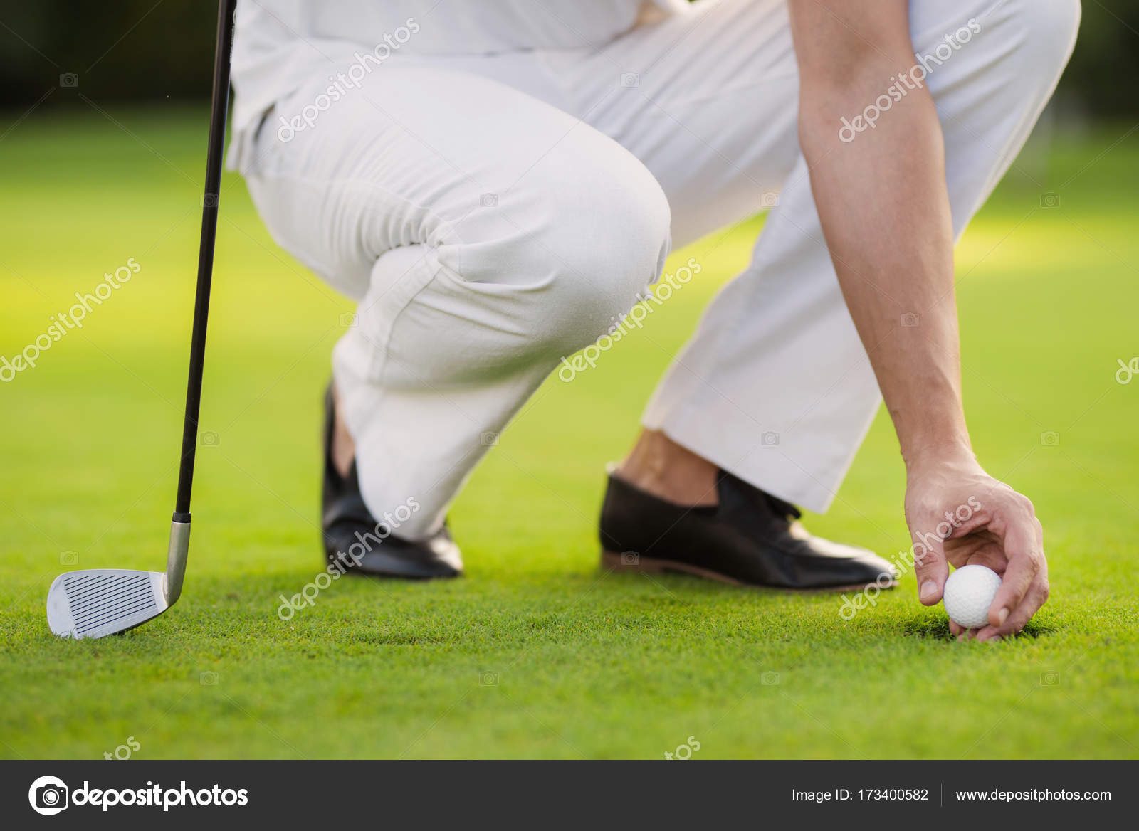 Close A man in white trousers and black shoes with a golf club