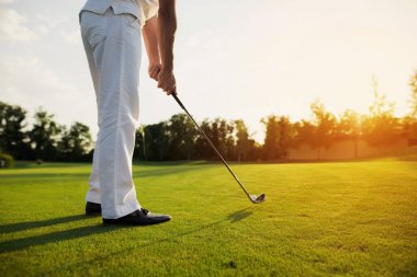 Beyaz takım elbise ve siyah ayakkabılar bir adam golf oynuyor