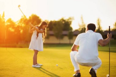 Bir adam bir golf kulübü çömelme ve topu grev için bir kulüp sallanan bir kız arıyor