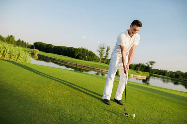 Um homem está de pé em um campo de golfe e se preparando para bater a bola com um taco de golfe — Fotografia de Stock