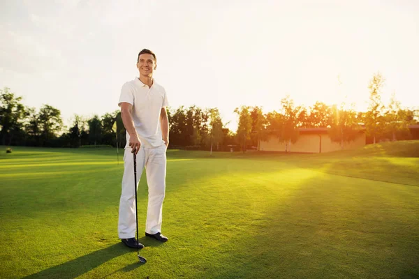 Um golfista profissional. Um homem está posando em um campo de golfe com um pau na mão — Fotografia de Stock