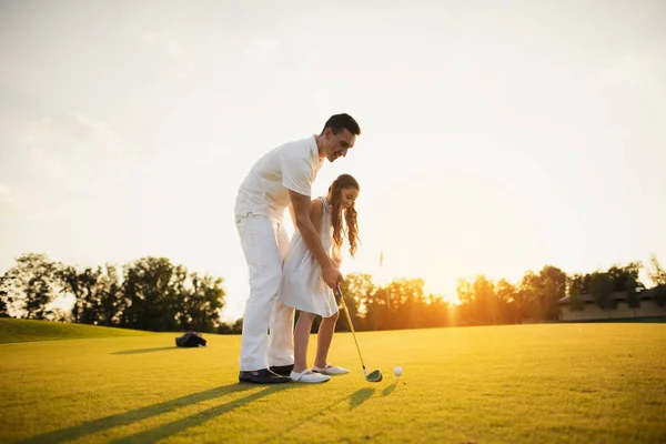 En tjej lär sig att spela golf med sin far — Stockfoto