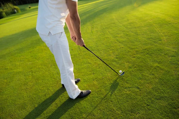 Close up. A man in a white suit is preparing to hit the ball with a golf club — Stock Photo, Image