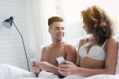 Genç bir çift yatakta oturuyor. bir adam ve bir kız onların akıllı bir şey izliyor.