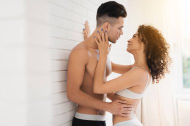 Genç çift yatak odasında. Duvar tarafından yatak odasında duruyorlar. Kız yavaşça adam hugs.