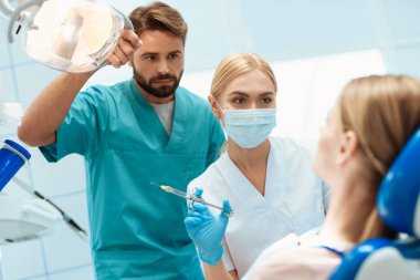 Kadın ve erkek diş hekimleri diş bir sandalyede oturan bir kız tedavi