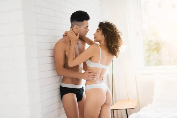 Pareja joven en el dormitorio. Están en el dormitorio junto a la pared. La chica gentilmente abraza al chico . — Foto de Stock