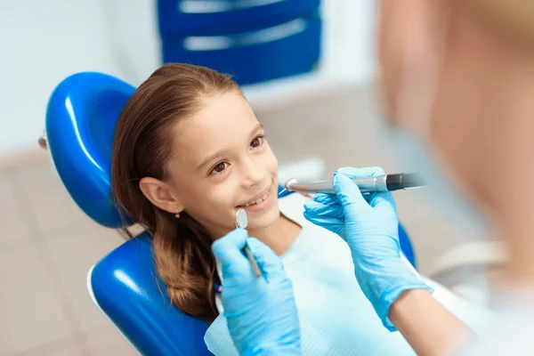 Een klein meisje bij een receptie met een tandarts. Vrouwelijke arts voorbereiding te onderzoeken van de tanden van een meisje — Stockfoto