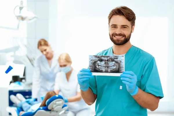 In der Zahnmedizin wird der Kiefer geröntgt. Vor dem Hintergrund seiner Kollegen behandeln sie ein kleines Mädchen — Stockfoto